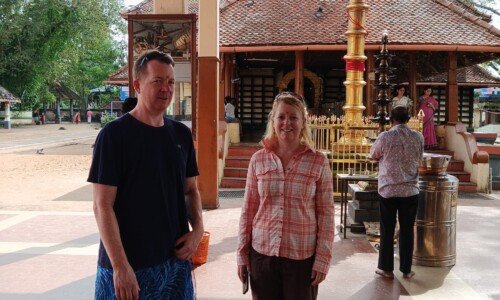 Visitors exploring a traditional temple in Alleppey, Kerala, surrounded by lush greenery.